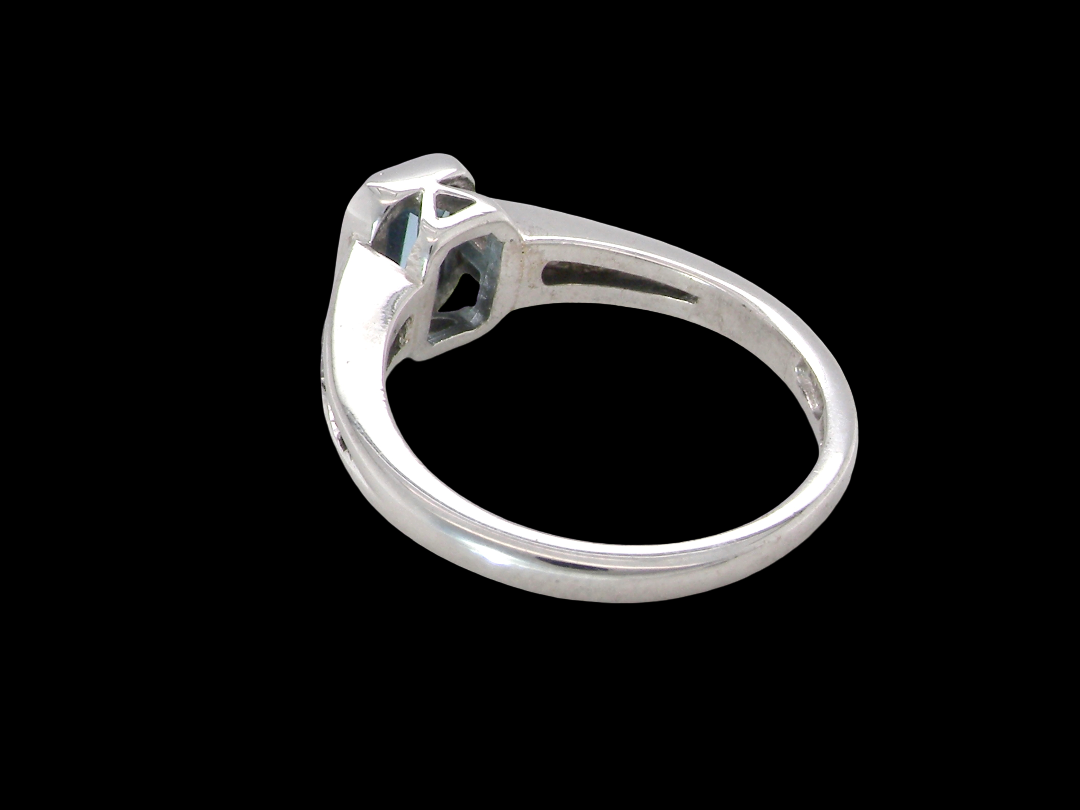 rear An 18 carat white gold ring, features a rectangular step cut aquamarine, measures 7x5mm (st one carat) sky blue, fine clarity. Rim setting.