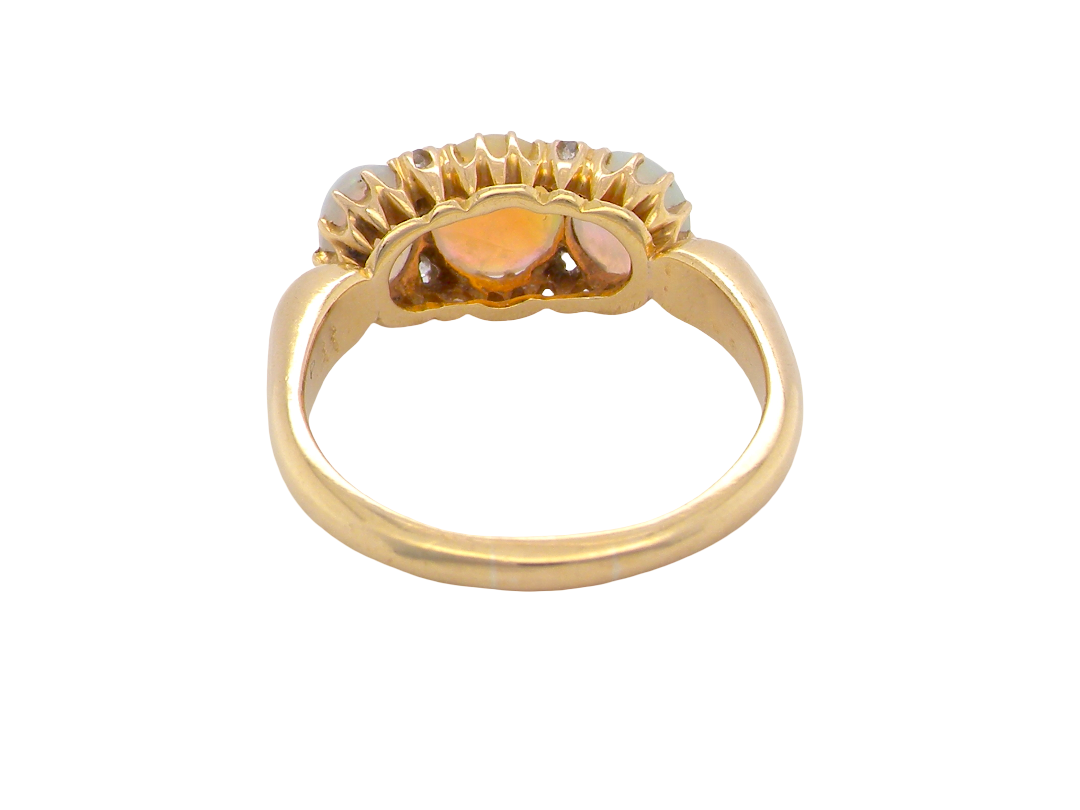 A vintage gold ring with a scalloped top setting featuring three amber-orange heart-shaped stones, shown on a plain white background.