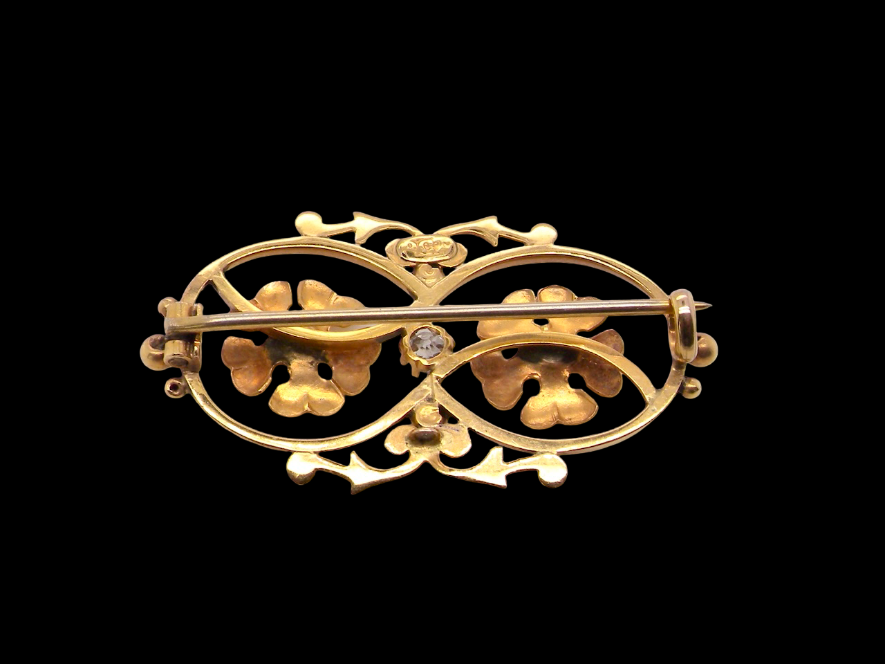 Gold brooch with floral design on a black background