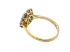 A yellow gold ring with a decorative cluster setting featuring small clear stones and a central green gemstone, shown on a plain white background.