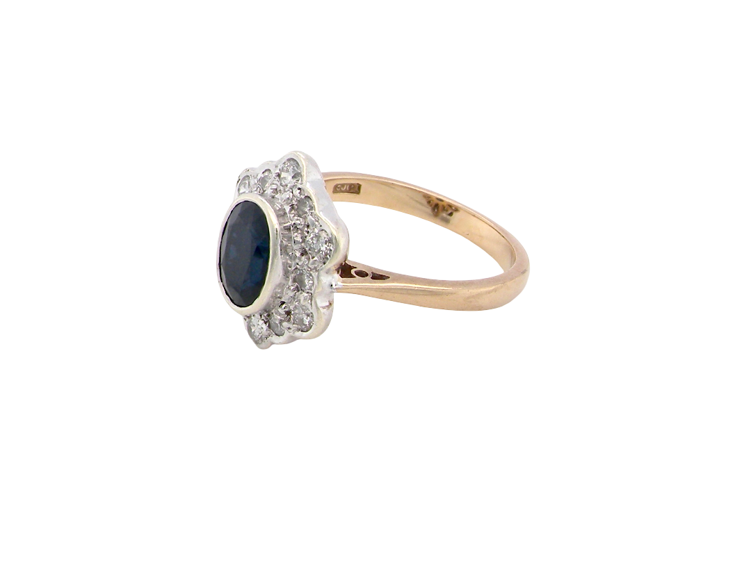 side A 9 carat gold cluster ring that features an inky black blue oval cut sapphire. This measures 8x6mm in a safe rim style setting 