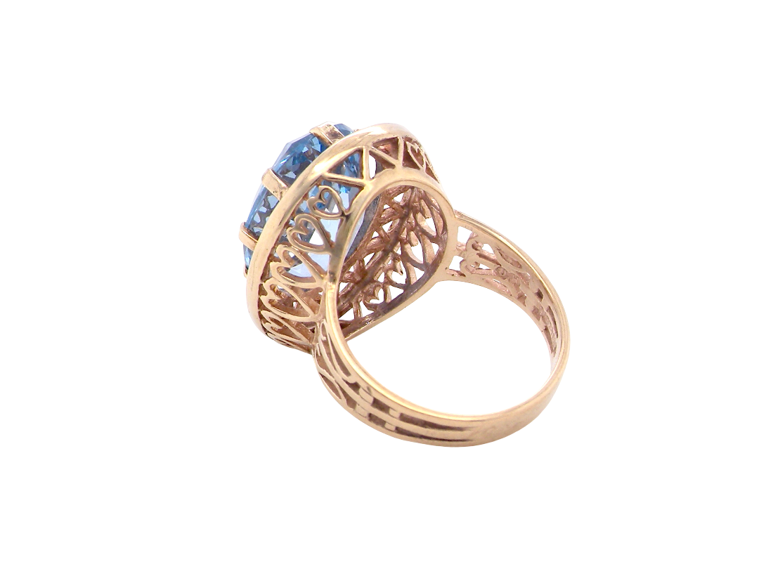 A 9 carat gold dress ring that features a large oval cut blue topaz gemstone. Measures 17x12mm. The head has a pierced outer border,