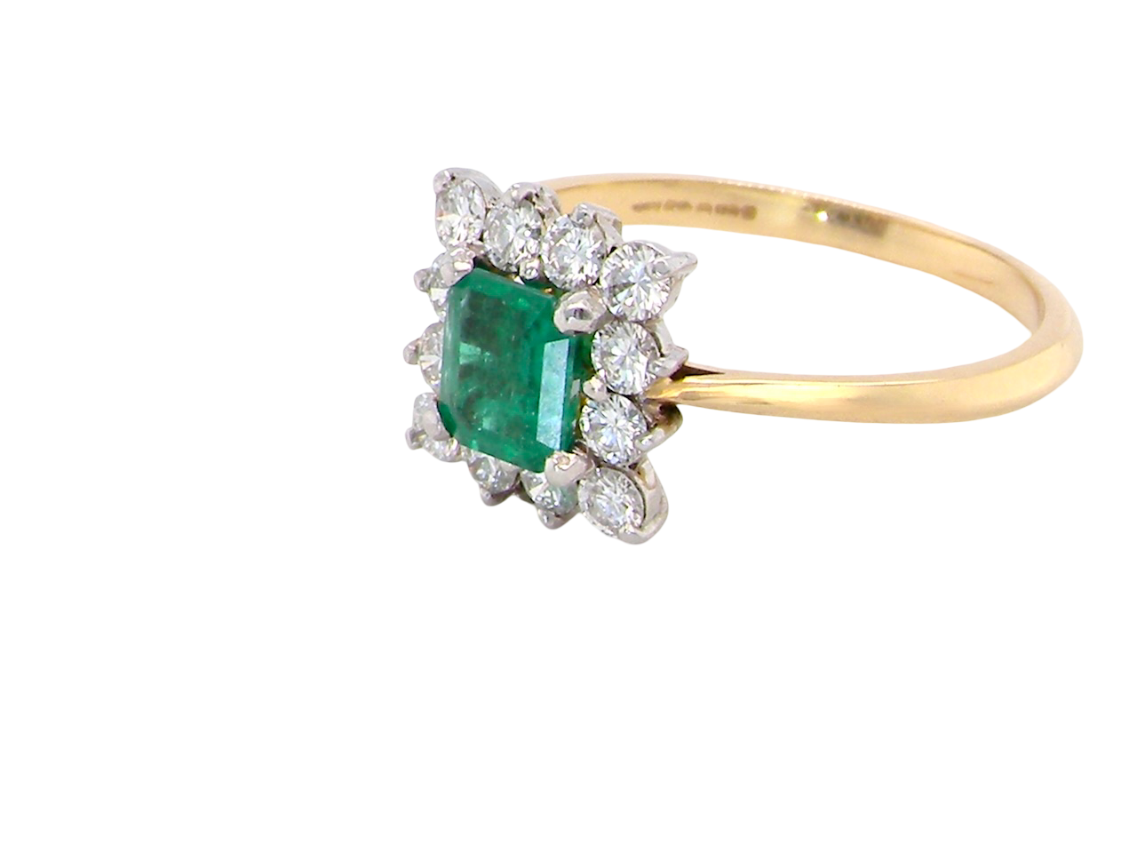 side A lcluster ring that features to the centre a rectangle shaped emerald, 7x5mm. Shows a deep grass green colour which does have natural inclusions common with most emeralds, but the depth of colour is impressive.