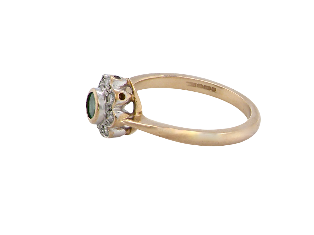 A vintage yellow gold ring with a cluster setting featuring a round green gemstone and small clear stones, shown on a plain white background.
