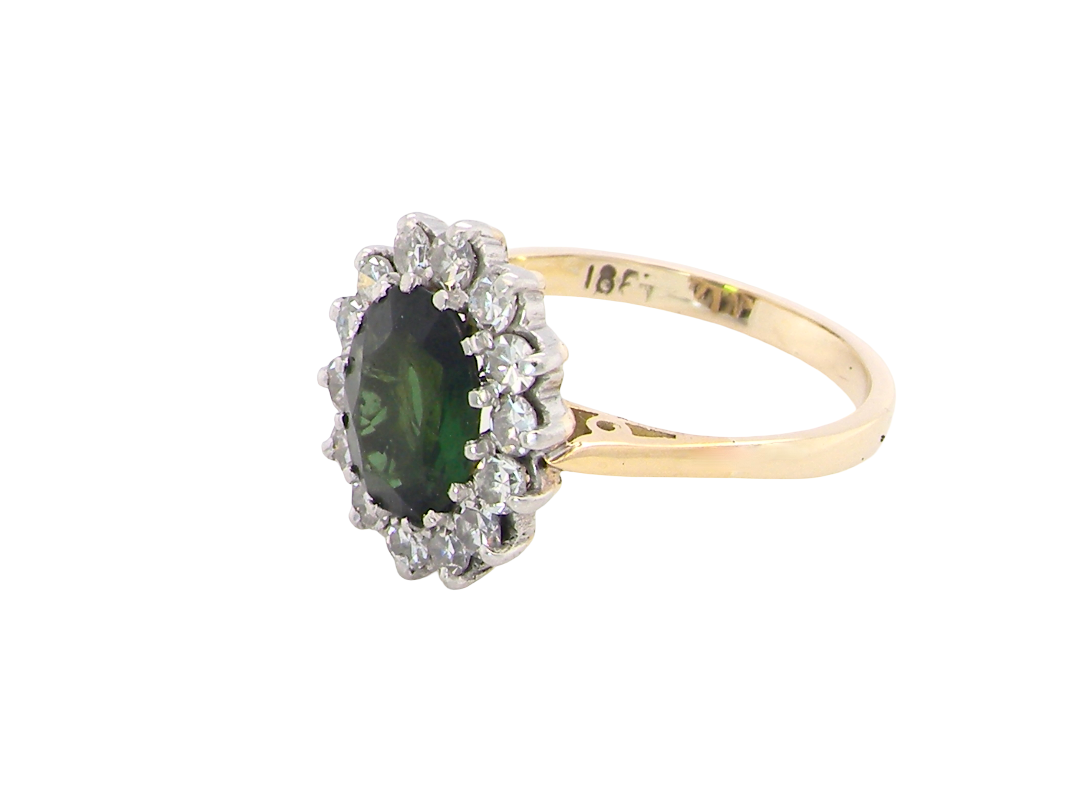 side A fine and impressive vintage cluster ring, centred with a striking oval-cut deep dark green tourmaline, measuring 9 x 7mm and estimated to weigh approximately 2.00 carats.