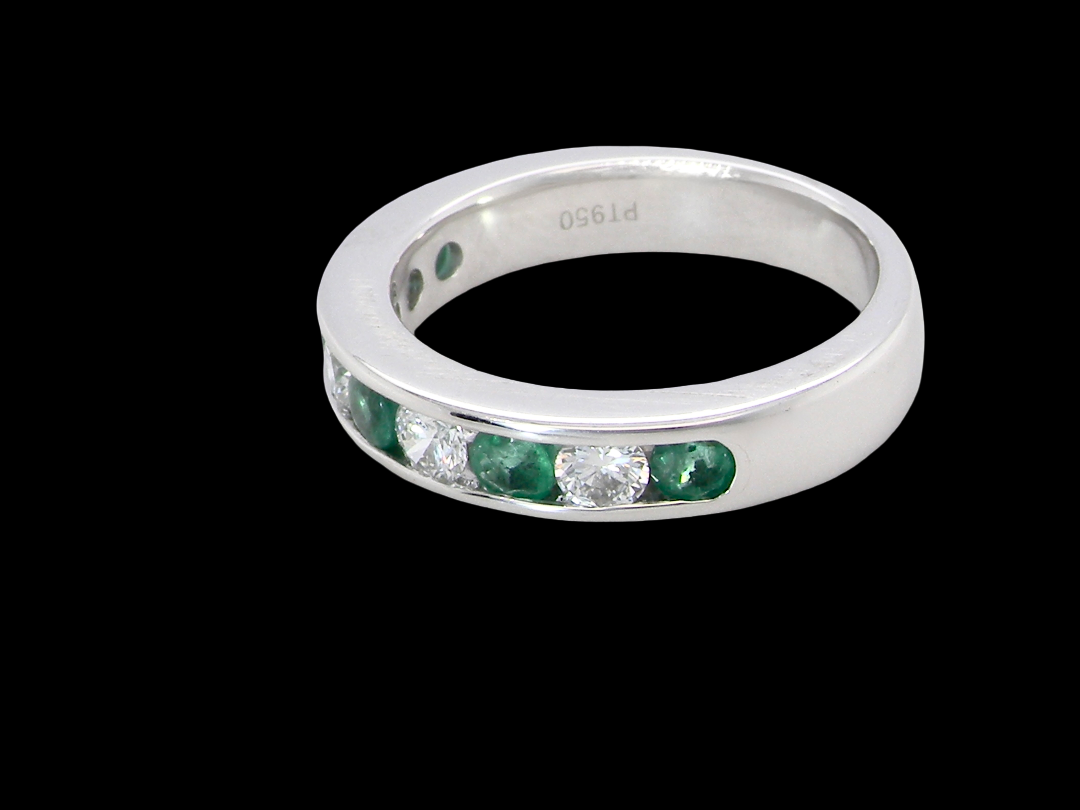 side A fine platinum half hoop eternity ring. This is a new ring*. Channel set gem stones, five bright green emeralds 2.6mm each (0.54 carats total)