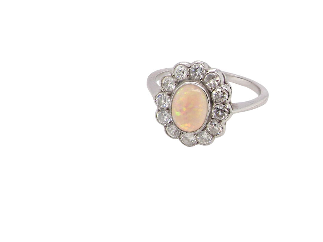 side A fine vintage cluster ring. Features to the centre an oval shaped opal, with excellent play of colour, pink to one way, vibrant green to the other with flashes of electric blue also within the body of the gem.
