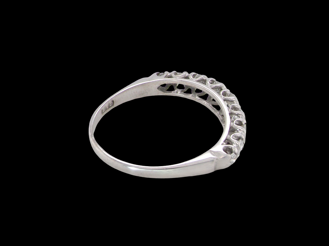 A ring with a curved, openwork filigree top featuring small clear stones, shown against a solid black background.