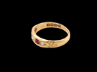 A vintage yellow gold ring with floral engravings and small gemstone accents, shown on a solid black background.