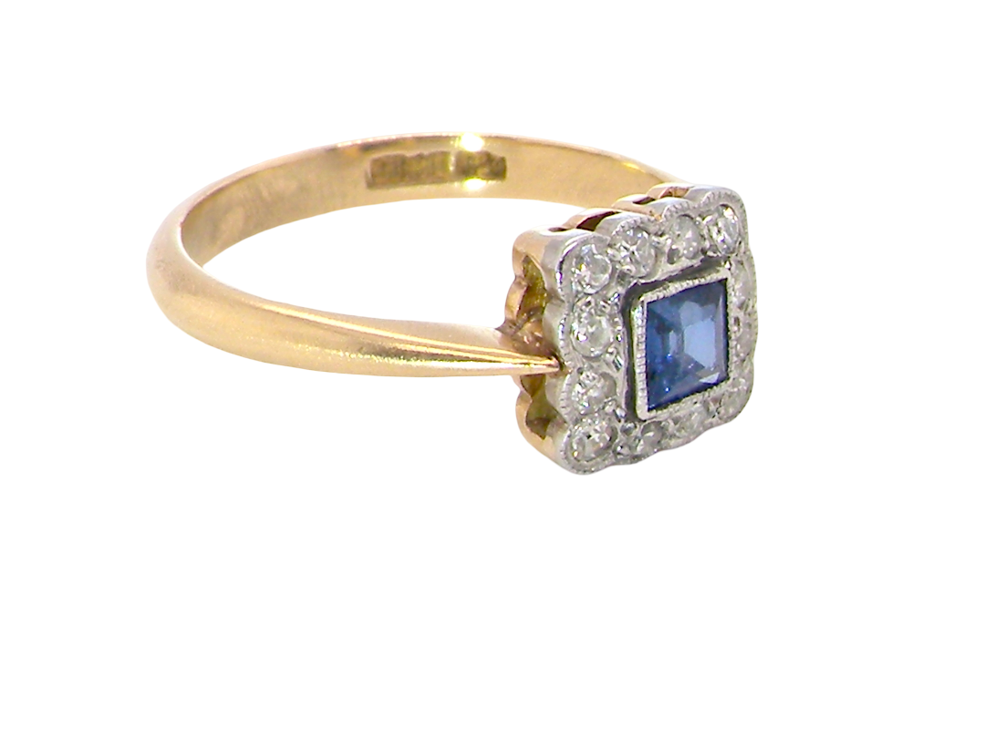 side A pretty square cluster ring. Features to the centre a cornflower blue square sapphire, 4x4mm (est 0.30 carats) mille grain set.

Complimented by a halo of twelve x 1.5 mm single cut white diamonds 