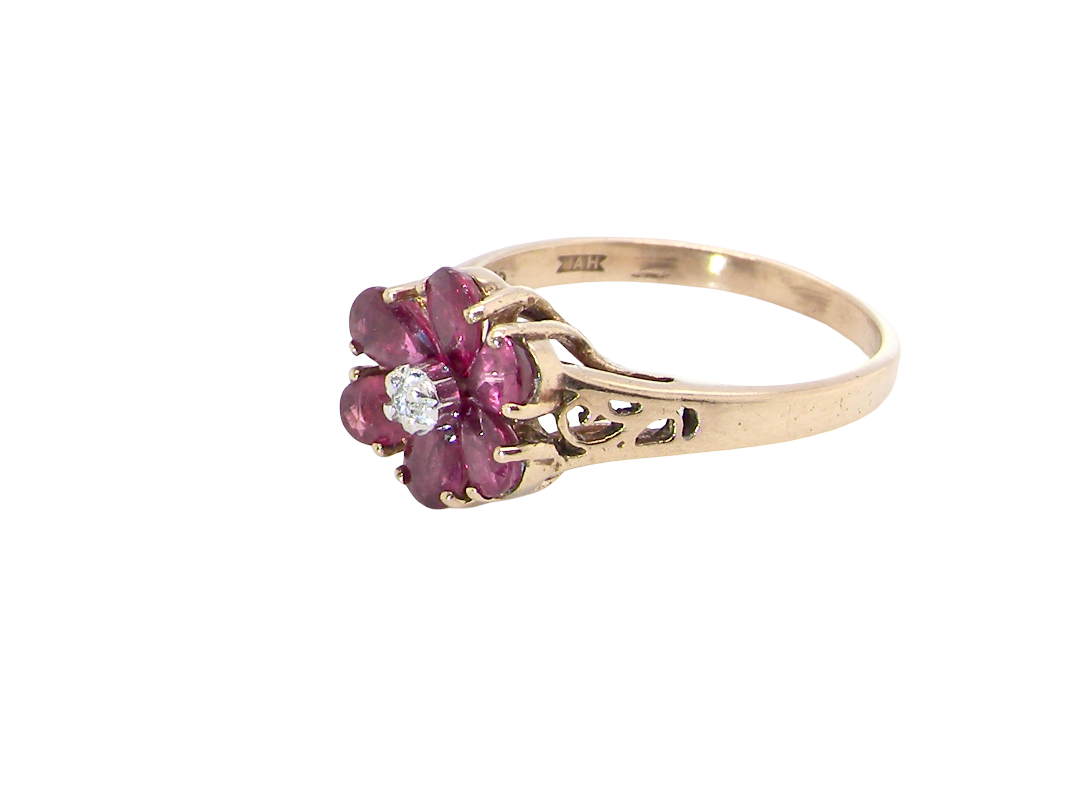 side A very pretty 9 carat gold cluster ring. The centre stone a small illusion set diamond, 1.3mm

Surrounded by six pear shaped raspberry red rubies,