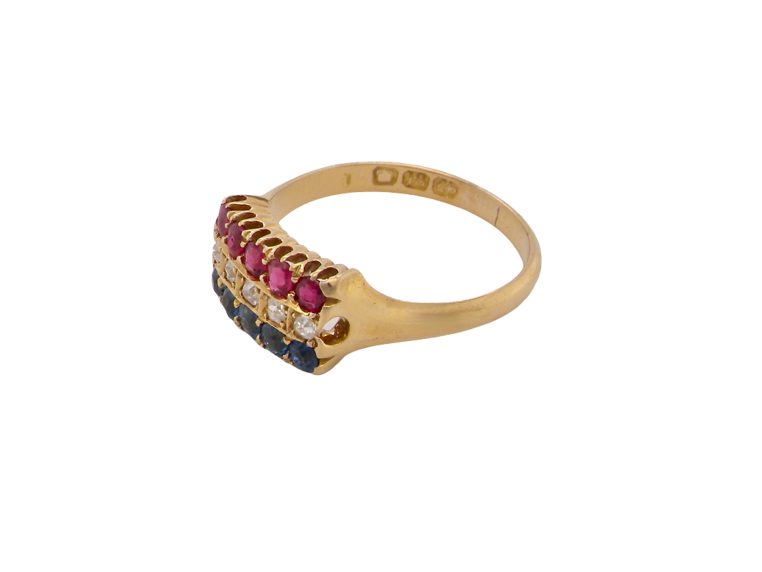 A vintage gold signet ring featuring a row of pinkish-red round stones, small clear stones, and dark blue round stones on a plain white background.