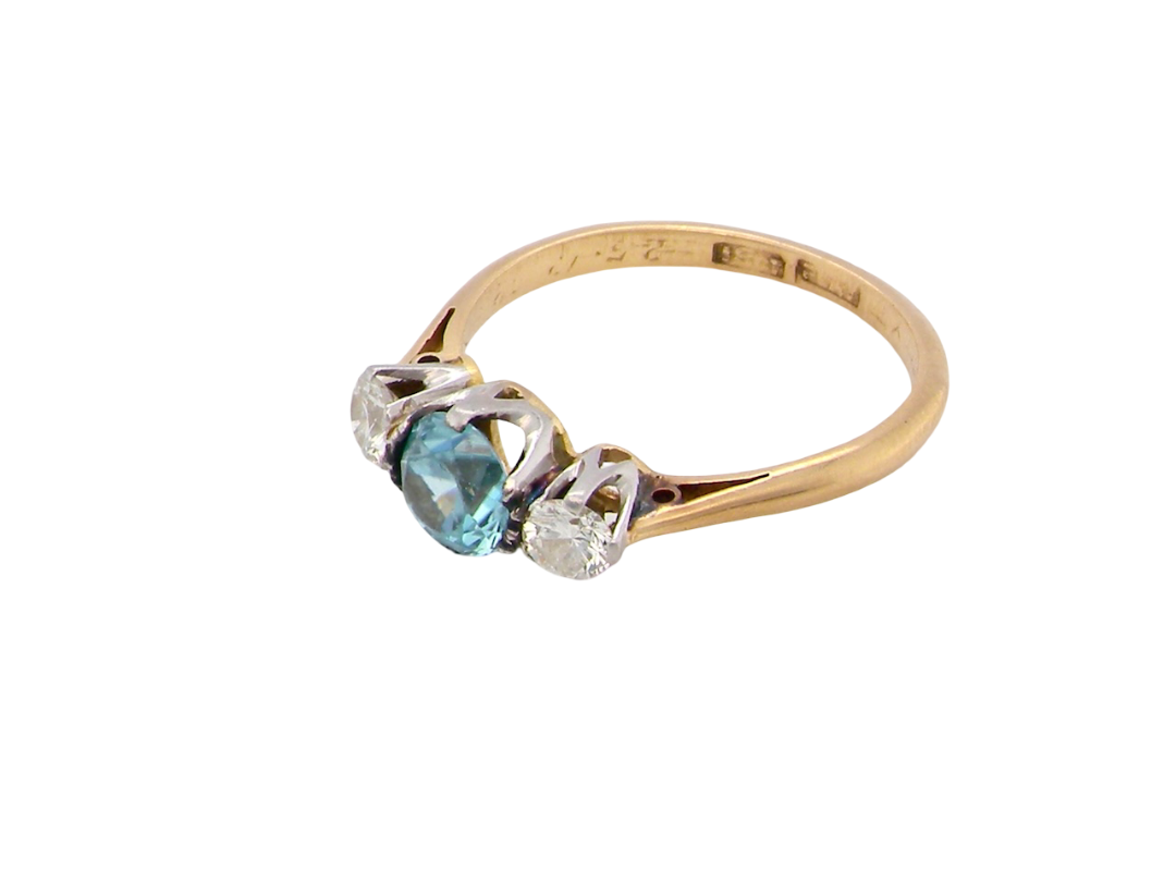 side A vintage three stone ring. Centre stone, a round 5.8mm natural blue zircon.

To each side an old brilliant cut white diamond 4mm round (est 0.25 carats). Colour i-j, clarity Si.