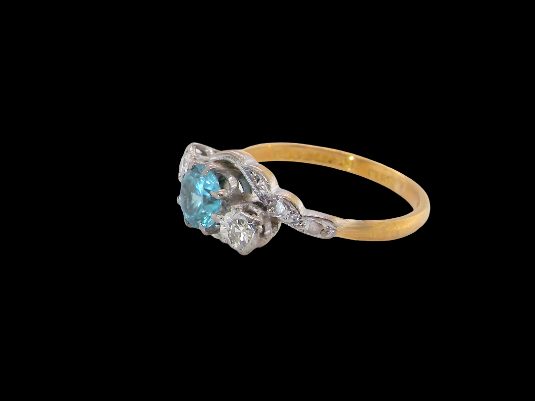 side A vintage three stone ring, cross over style and features a round 6mm&nbsp; natural blue zircon centre stone