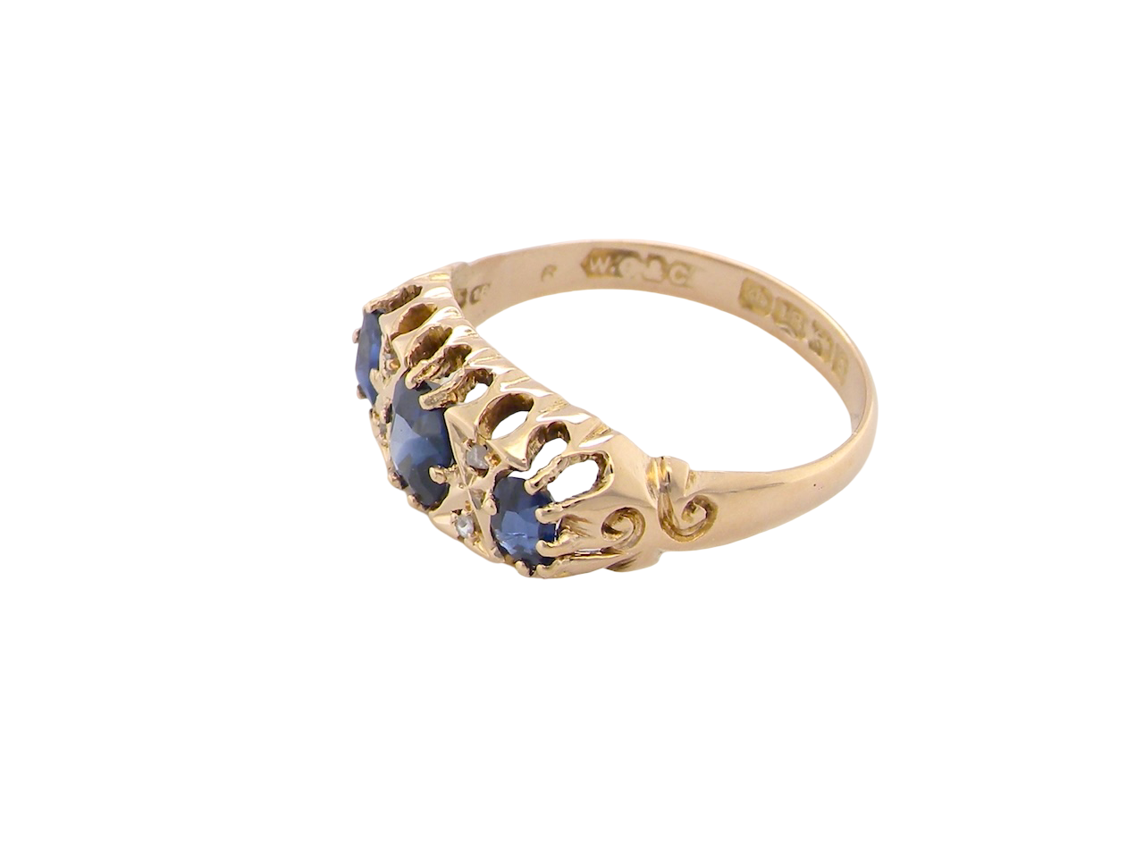 side An 18 carat gold antique boat shaped ring. Features three oval to cushion cut sapphires, centre 6x5mm, each end 5x3mm. Mid to dark blue
