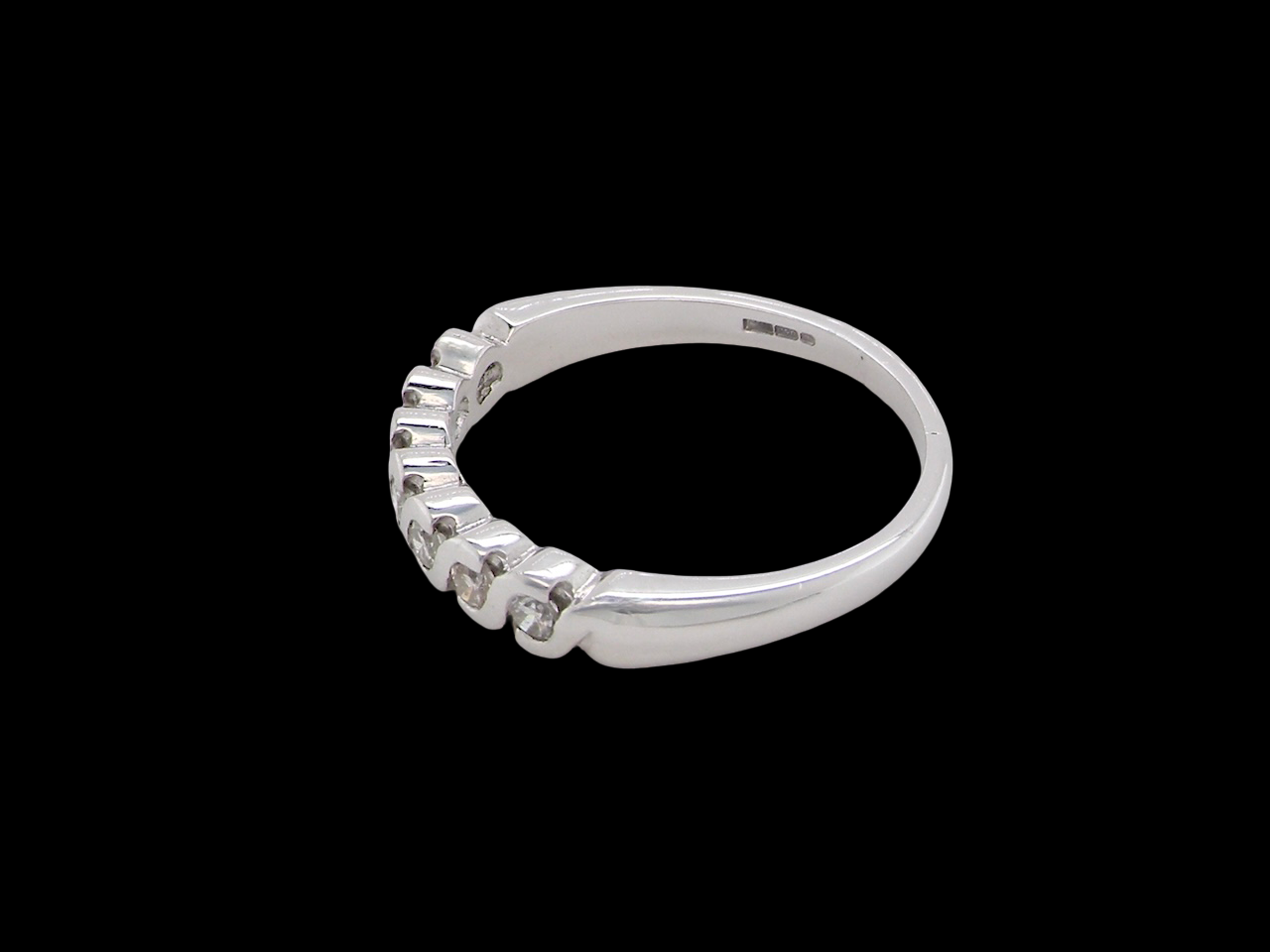 side An 18 carat white gold half hoop eternity ring. Set with seven brilliant cut white diamonds,