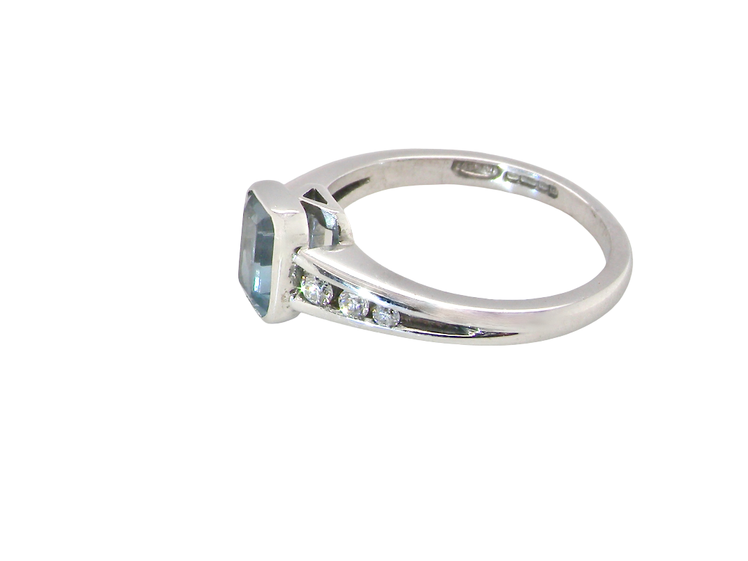 side An 18 carat white gold ring, features a rectangular step cut aquamarine, measures 7x5mm (st one carat) sky blue, fine clarity. Rim setting.