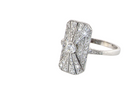 side An Art Deco panel shaped cluster ring. The head measures 16x10mm, depth 3.4mm, and has two fan shaped designs that feature above and below a brilliant cut white diamond centre stone which measures 3.4mm (0.15 carats est)
