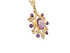Gold pendant with purple gemstones on a white background