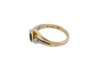 side An elegant 18 carat gold three-stone ring featuring a rich, oval-cut dark blue sapphire at the centre, measuring 5 × 4mm, secured in a classic rim (bezel) setting.