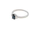 side An elegant three-stone ring crafted in 18 carat white gold, featuring a striking rectangular dark blue sapphire at the centre, measuring 6 × 4 mm and weighing approximately 0.50 carats.