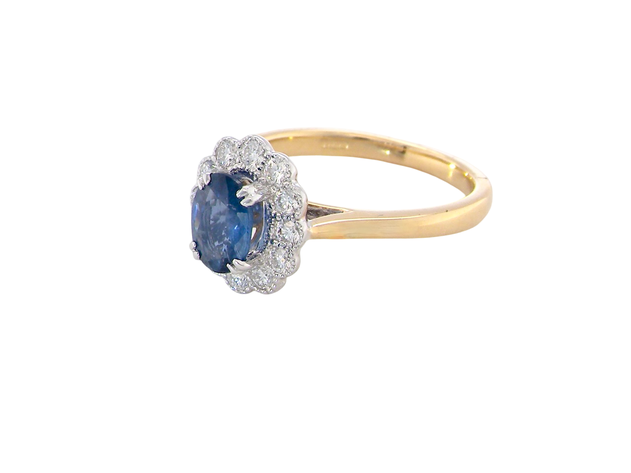 side A  cluster ring featuring an oval-cut mid to dark blue sapphire measuring 7 × 5 mm (approximately ¾ carat).