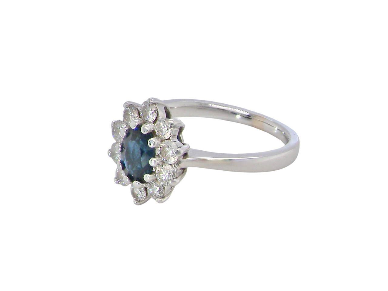 side  fine 18 carat white gold cluster ring. Features an oval cut dark blue sapphire centre stone 