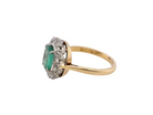 side of an  enchanting cluster ring that features at its centre an oval emerald, 