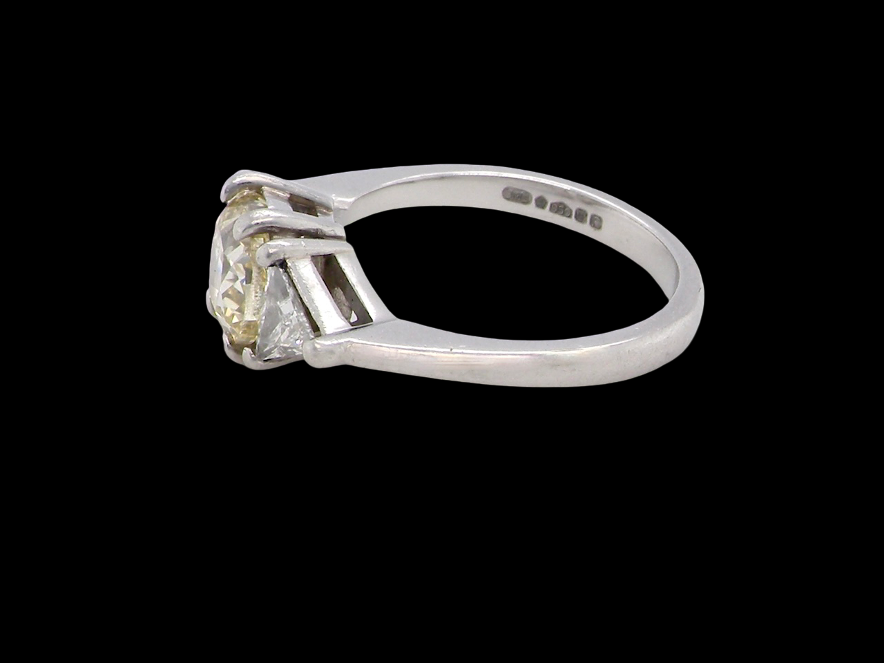 side striking and elegant trilogy ring crafted in 18-carat white gold, set with a vibrant fancy yellow cushion-cut diamond