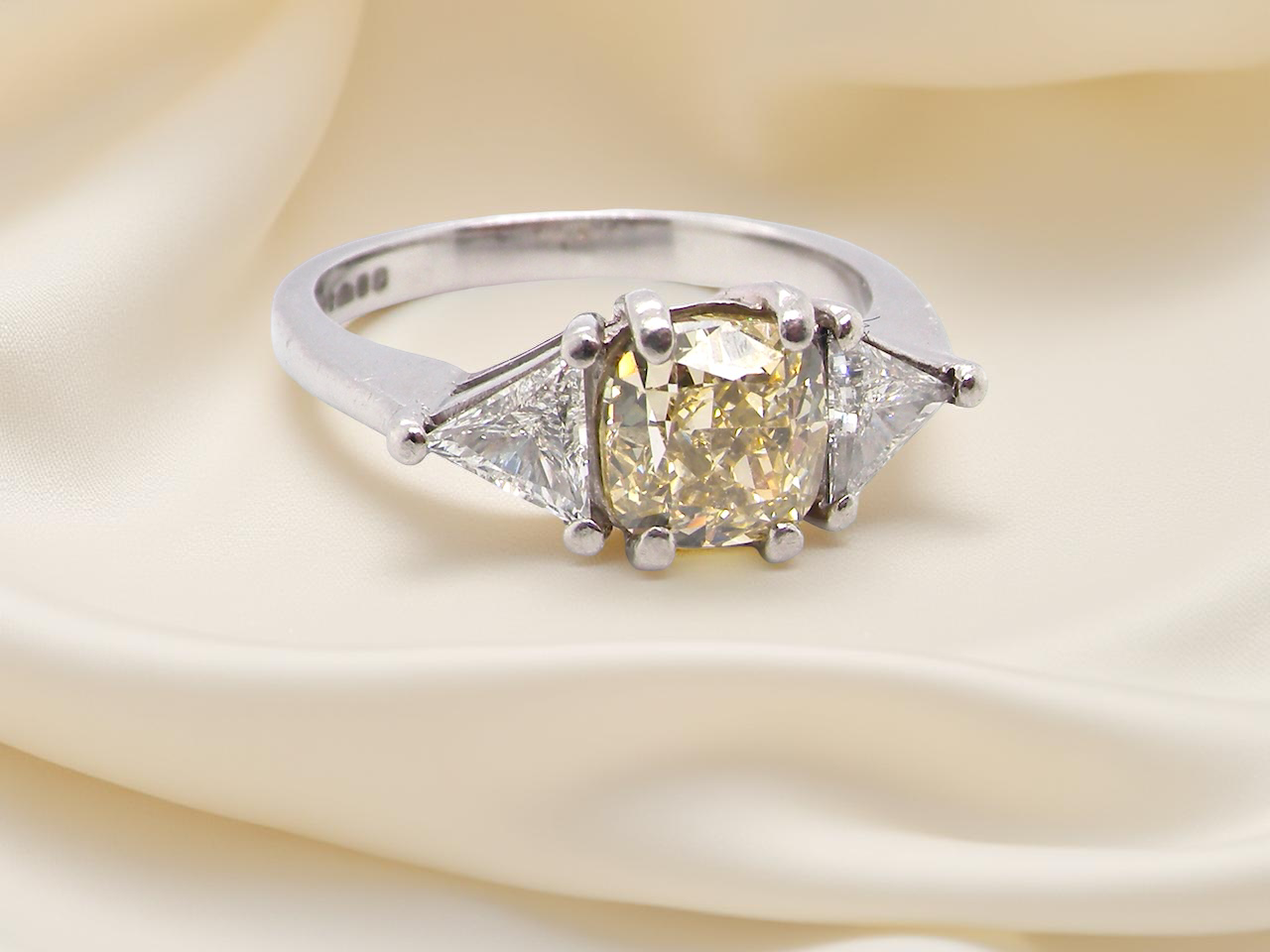 striking and elegant trilogy ring crafted in 18-carat white gold, set with a vibrant fancy yellow diamond