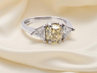 striking and elegant trilogy ring crafted in 18-carat white gold, set with a vibrant fancy yellow diamond