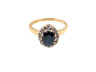 top An elegant 18 carat gold cluster ring featuring a striking inky dark blue sapphire at its centre. 
