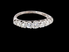 A  ring set with a row of round-cut clear gemstones, photographed against a solid black background.