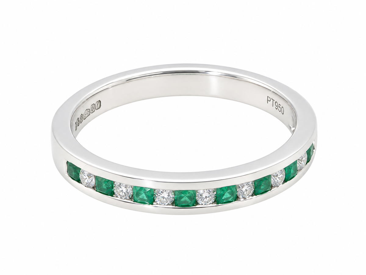 an  eternity ring featuring a channel setting of round-cut green emeralds and clear diamonds. The inner band is engraved with 'M390' and 'PT950'.