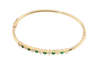 top view A yellow gold bangle. Features alternate emeralds and diamonds. Six 2.7mm emeralds and seven brilliant cut white diamonds, each 2.7mm (total diamond total 0.50 carats)
